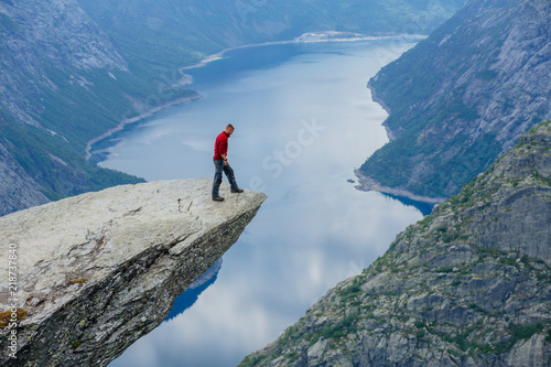 Man in blue sportswear standing on trolltunga in Norway. photo