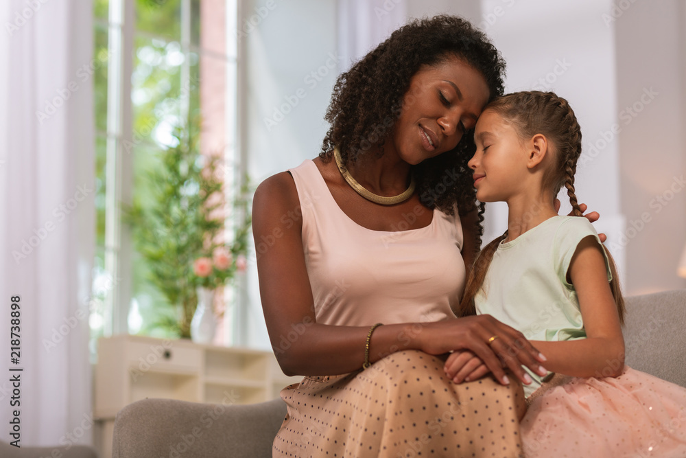 Obraz premium Happy motherhood. Pleasant caring mother smiling while being together with her daughter