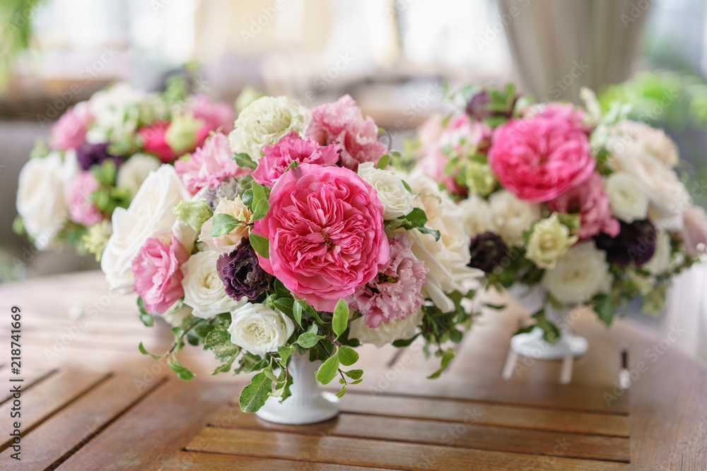 Arrangement of fresh flowers in pastel colors. Wedding background. table in a restaurant. different varieties of garden and shrub roses in a light vase on wooden table