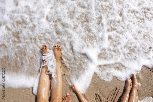 Fototapeta Naklejka Na Ścianę i Meble -  Family feet wet by the sea waves at the beach in summer holiday
