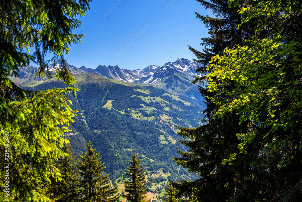 Obraz premium Scenic view of beautiful landscape in Swiss Alps. Fresh green meadows and snow-capped mountain tops in the background in springtime, Switzerland.