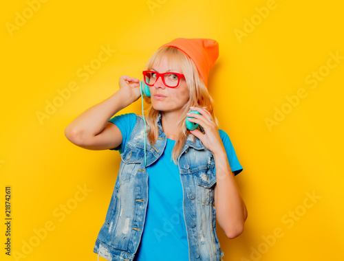 portrait of trendy adult girl orange hat with headphones on yellow background