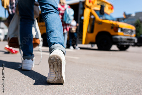 cropped shot of student walking at school bus with classmates