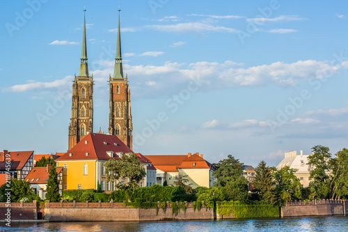 medieval old city street view with red roofs of small house and gothic tower of catholic church on blue sky background in colorful summer bright contrast day time