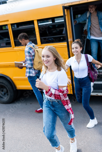 active happy teen scholars running out school bus