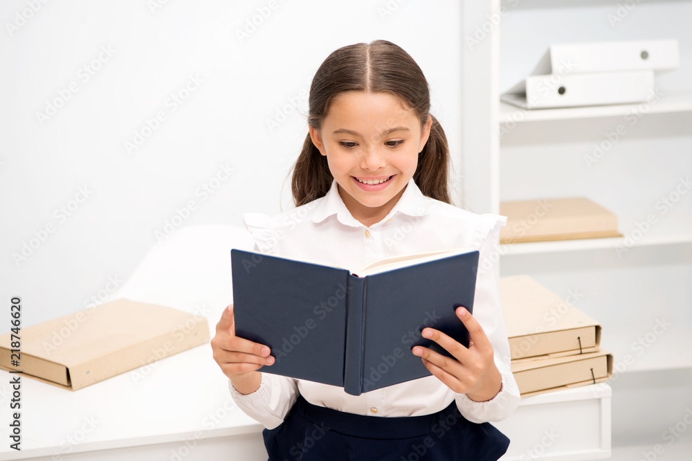 Exciting literature concept. Girl child read book stand white interior. Schoolgirl studying textbook. Kid girl school uniform happy face read book. Excited about knowledge. Such interesting topic Exciting literature concept. Girl child read book stand white interior. Schoolgirl studying textbook. Kid girl school uniform happy face read book. Excited about knowledge. Such interesting topic