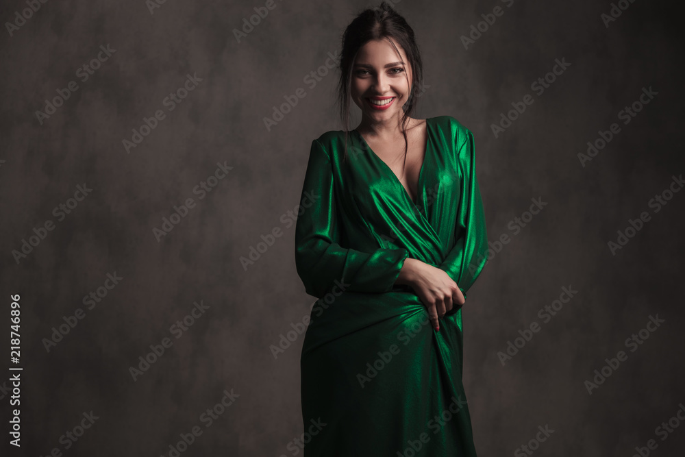 smiling brunette woman covering herself with her green dress