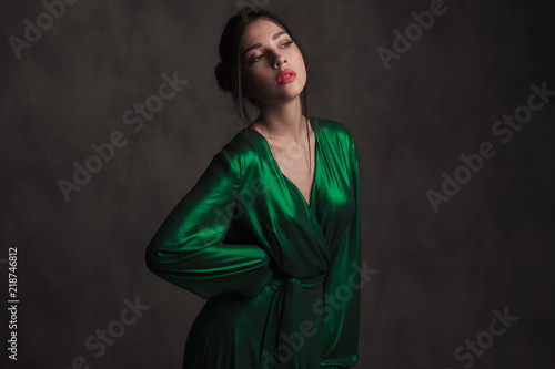 seductive brunnete woman in long green dress looks to side