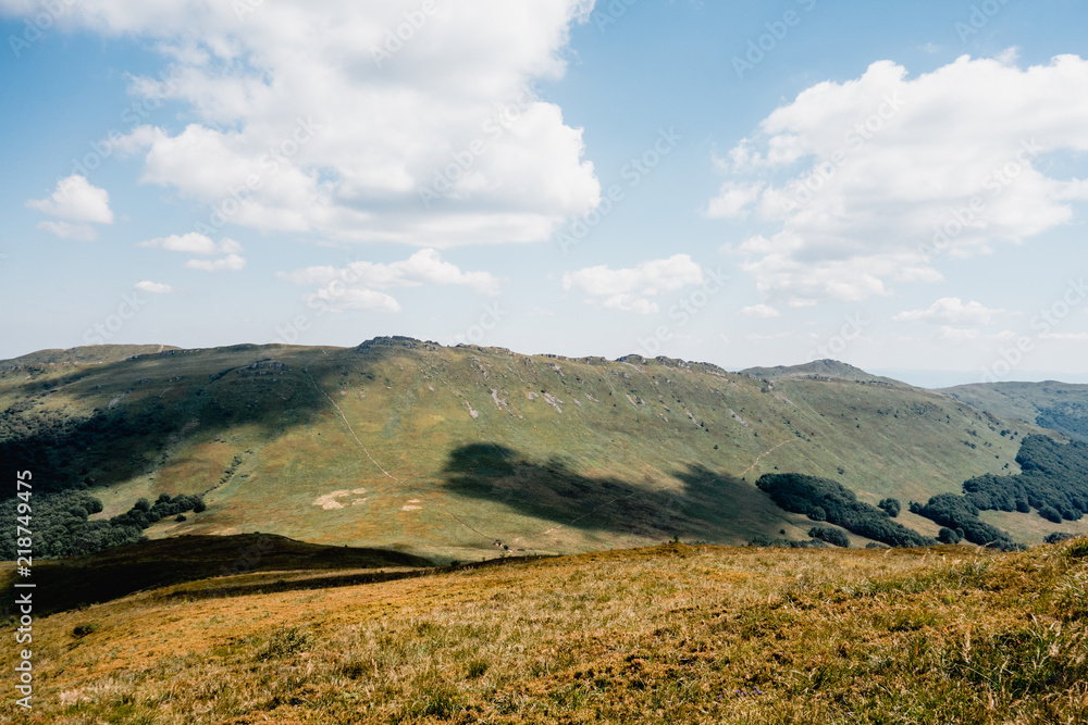 Aerial view of grassland in mountains with shadows on the peaks