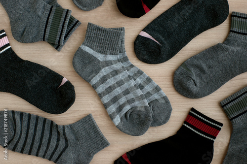 Knitted socks in gray tones. View from above. Many classic socks are scattered on the surface. Clothes for autumn and winter.