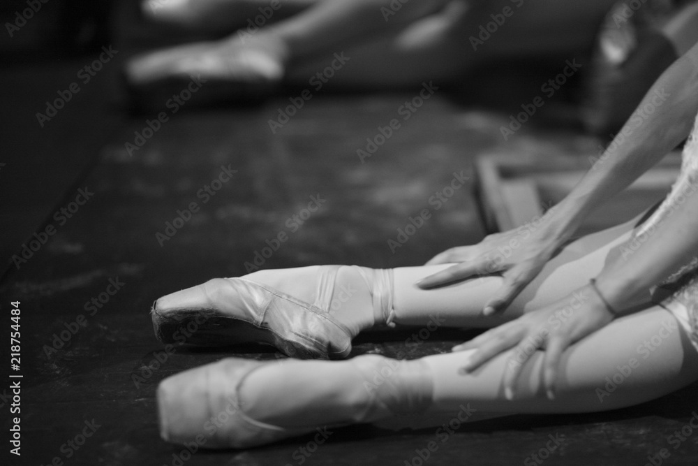 Ballerina in pointe shoes, sitting on the floor behind the scenes in the intermission of the ballet