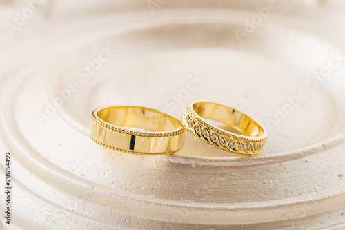 Two gold wedding rings on beige background
