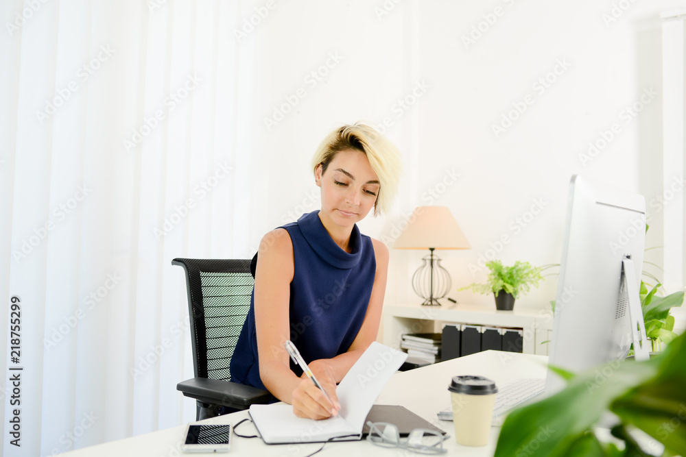 beautiful young business woman working at desk in a white and bright office
