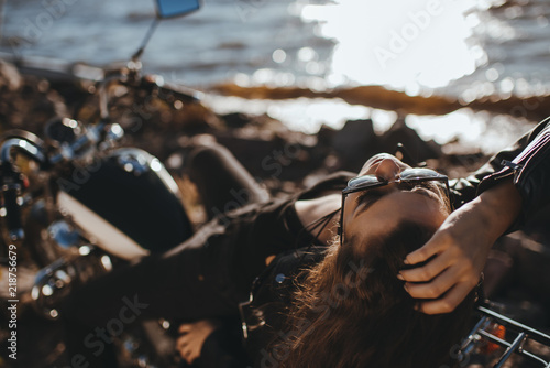 attractive woman in sunglasses relaxing on classical motorbike