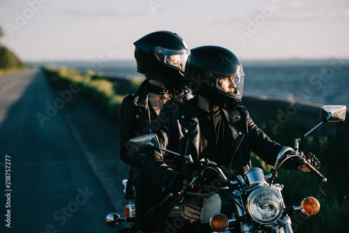 Obraz na plátně couple of bikers in helmets riding classical motorcycle on country road