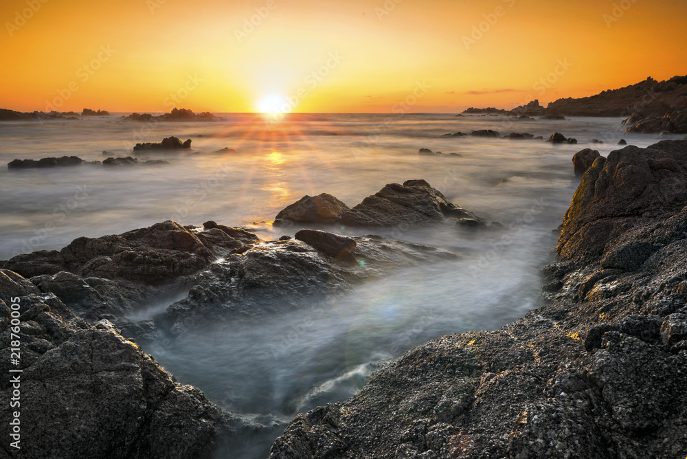 Romantic sunset over rocky coast and soft silky water