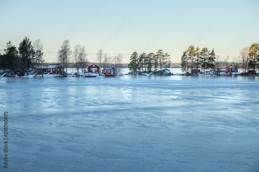 Winter landscape with red wooden house on a lake in Sweden.