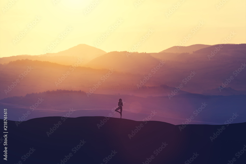 Woman standing on the hill, practicing yoga.