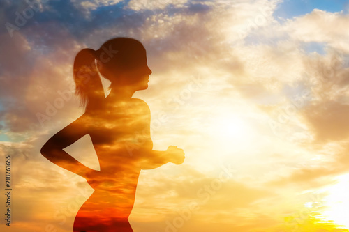 Silhouette of a running woman on sky background.