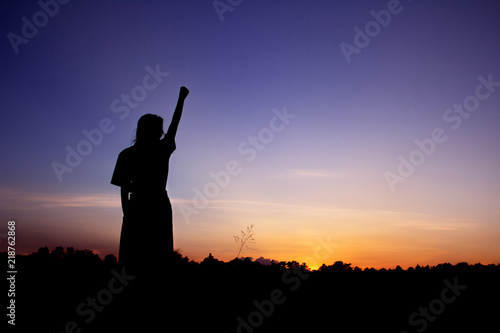 Happy celebrating winning success woman silhouette on sky background.