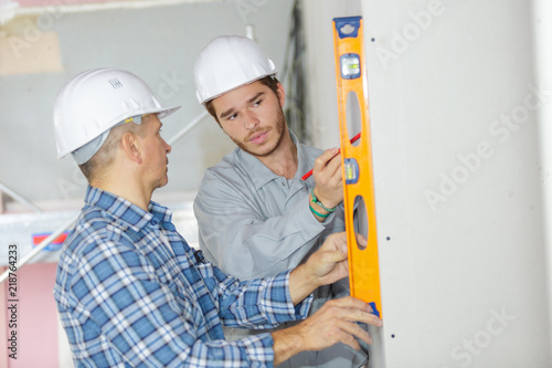 two workers with level indoors