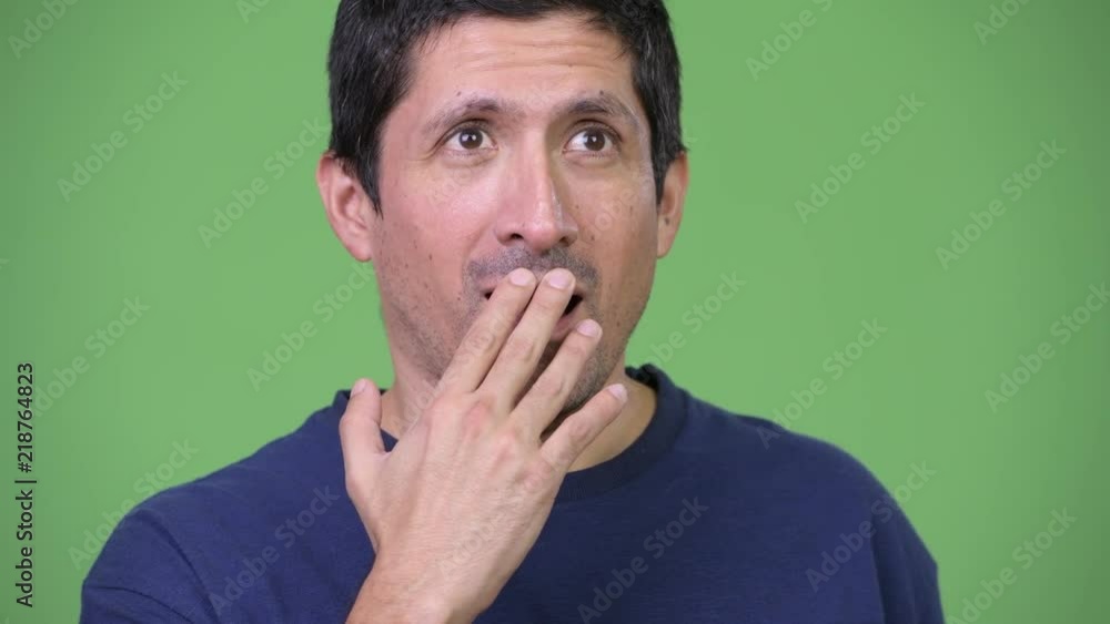Hispanic man covering mouth and looking guilty Hispanic man covering mouth and looking guilty