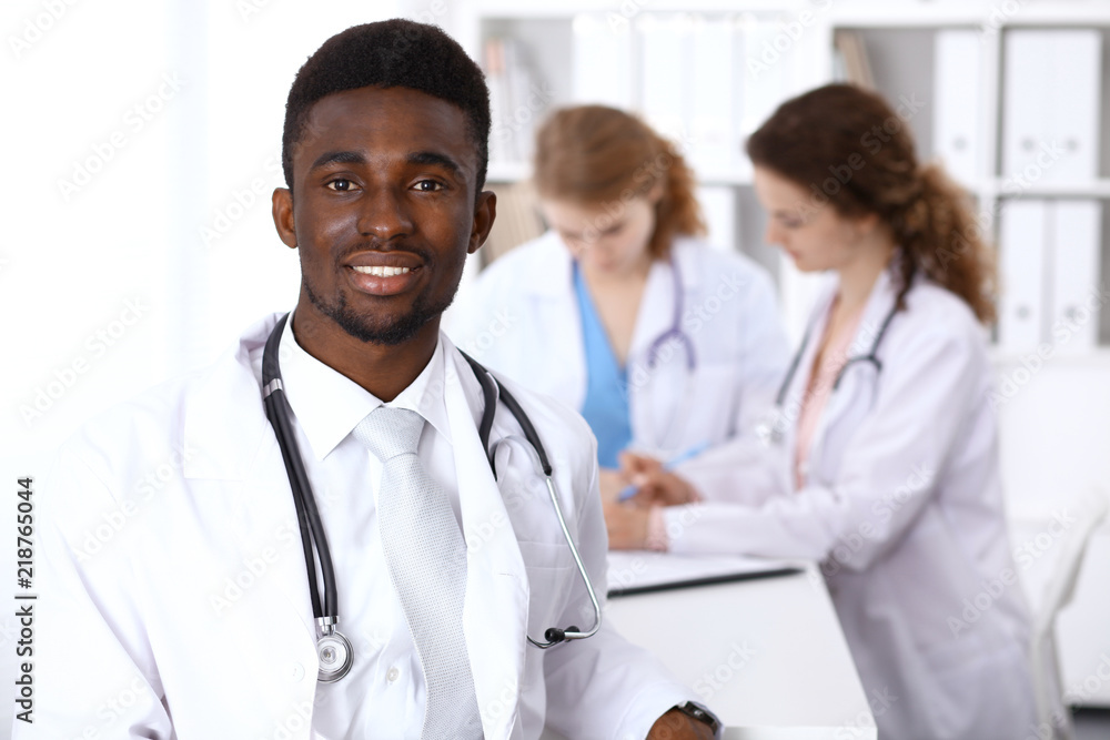Fototapeta premium Happy african american male doctor with medical staff at the hospital. Medicine concept