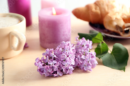 Beautiful blossoming lilac with burning candle on table