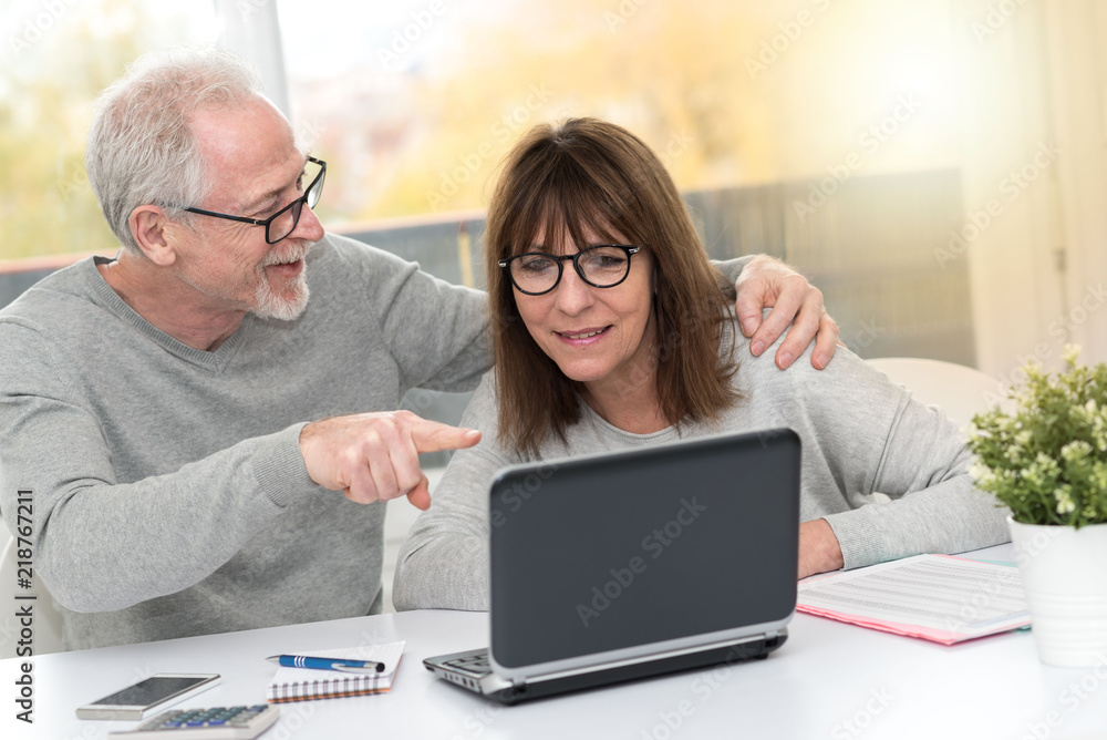 Happy mature couple having a good surprise on laptop, light effect Happy mature couple having a good surprise on laptop, light effect
