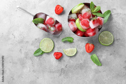 Composition with ice cubes, strawberries, mint and sliced lime on grey background