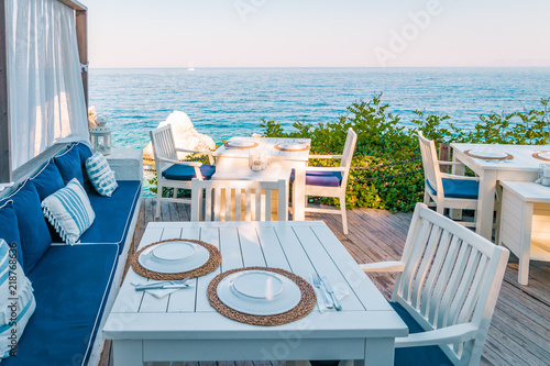 Fototapeta Naklejka Na Ścianę i Meble -  table and chairs on the cliff of an mountain bty the ocean restaurant look over ocean of Fethiye Turkey