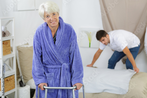 elderly woman ambulates from her bed with a walker