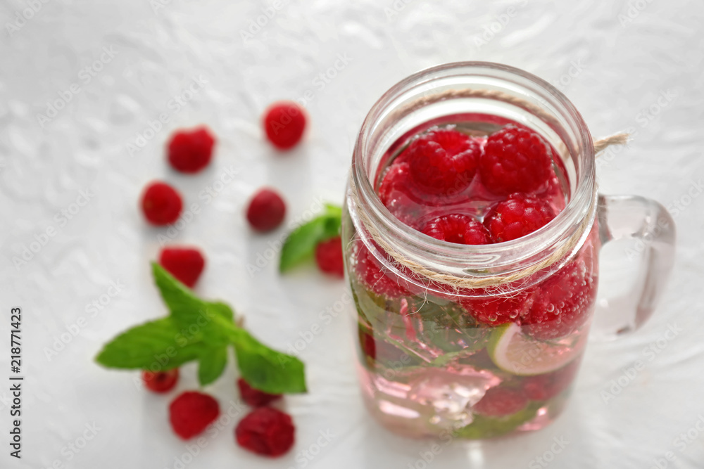 Mason jar of fresh raspberry mojito on white table Mason jar of fresh raspberry mojito on white table