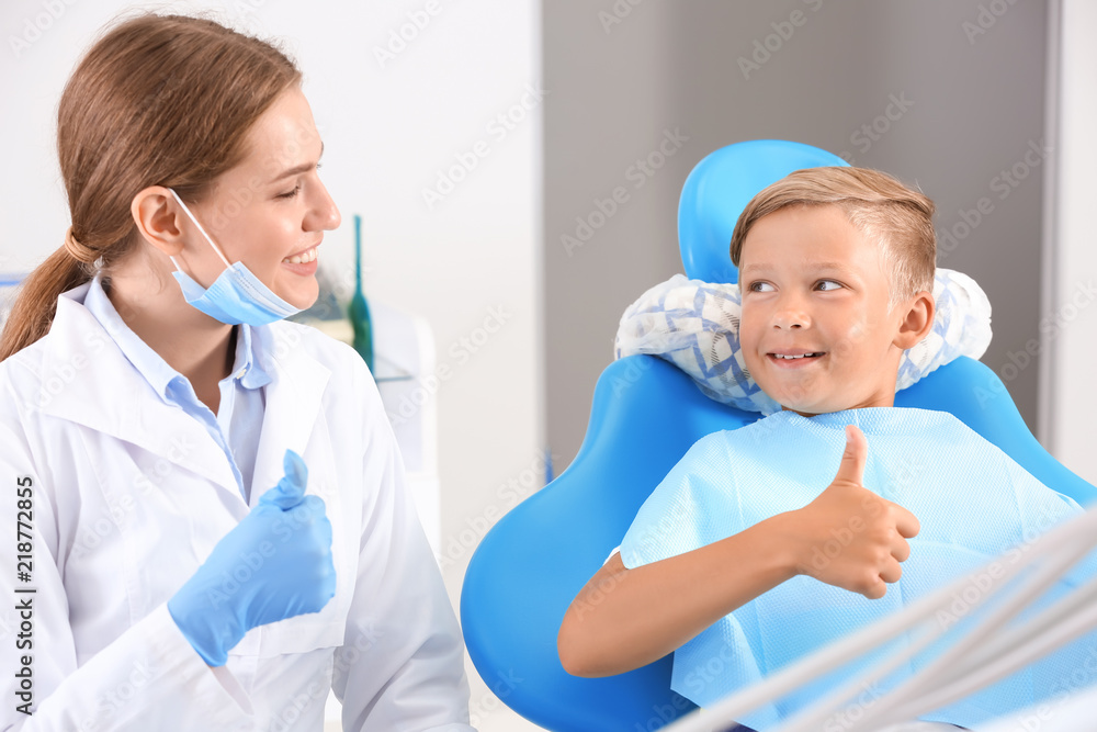 Cute little boy and dentist showing thumb-up gesture in clinic Cute little boy and dentist showing thumb-up gesture in clinic