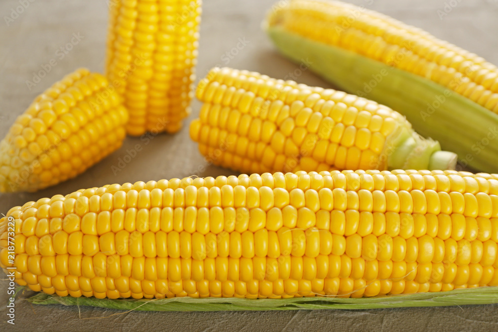 Fresh corn cobs on grey table, closeup Fresh corn cobs on grey table, closeup