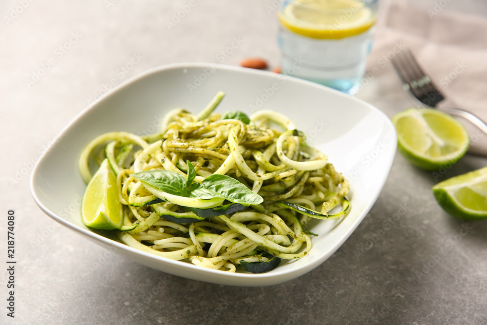 Plate of spaghetti with zucchini and pesto sauce on table