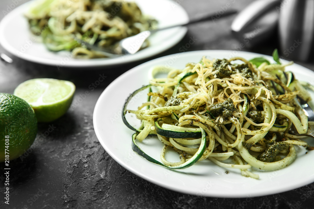 Plate of spaghetti with zucchini, pesto sauce and cheese on table, closeup