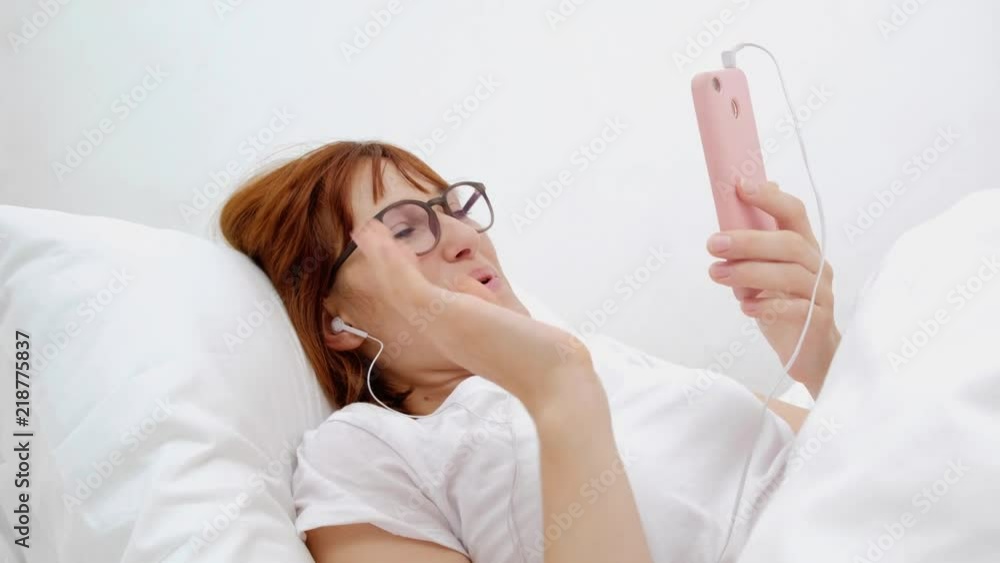 Patient talking on mobile phone in bed. Young attractive woman in hospital bed. Connected world and mobile office concept. Patient talking on mobile phone in bed. Young attractive woman in hospital bed. Connected world and mobile office concept.