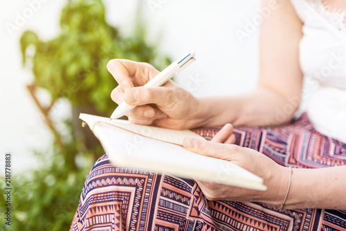 close-up of woman sitting on patio taking notes in notebook