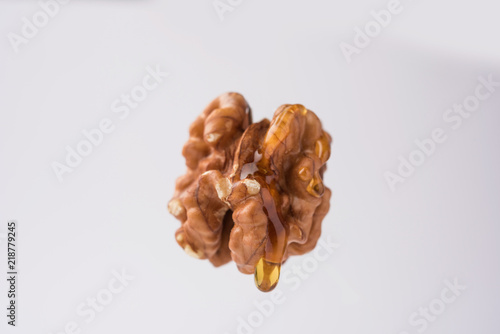 Golden walnut oil drop dripping fromnwhole Akrod/akhrot dry fruit, flying in the air isolated photo