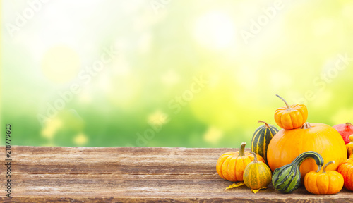 pile of orange pumpkins with fall leaves on wooden table over fall background banner