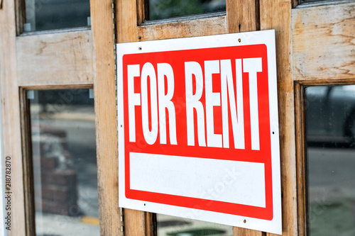 Closeup of red, white for rent sign attached, hanging on wooden apartment, house, home, building door with glass windows