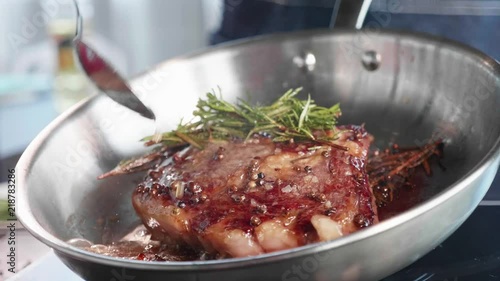 Meat steak is fried in oil and grease on frying pan, close-up in slow motion. photo