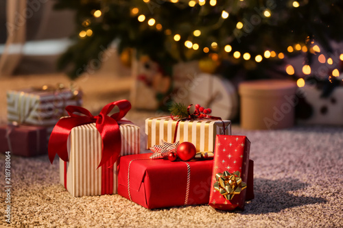 Tableau sur toile Beautiful Christmas gift boxes on floor near fir tree in room