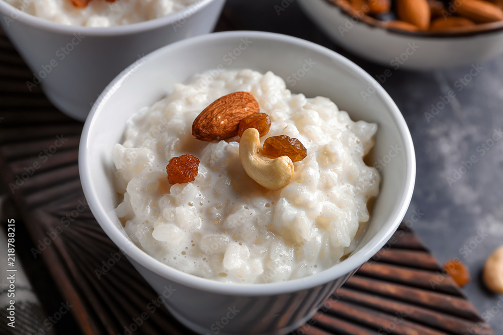 Delicious rice pudding with nuts and raisins in bowl on wooden board, closeup Delicious rice pudding with nuts and raisins in bowl on wooden board, closeup
