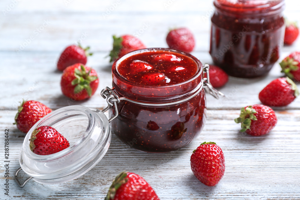 Glass jar with delicious strawberry jam on wooden table Glass jar with delicious strawberry jam on wooden table