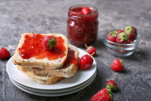 Plate with slices of bread and delicious strawberry jam on grunge table