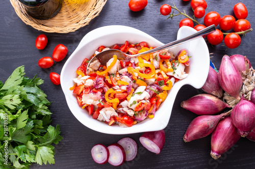 Insalata di baccalà alla catalana nel contenitore a forma di pesce in ceramica bianca photo