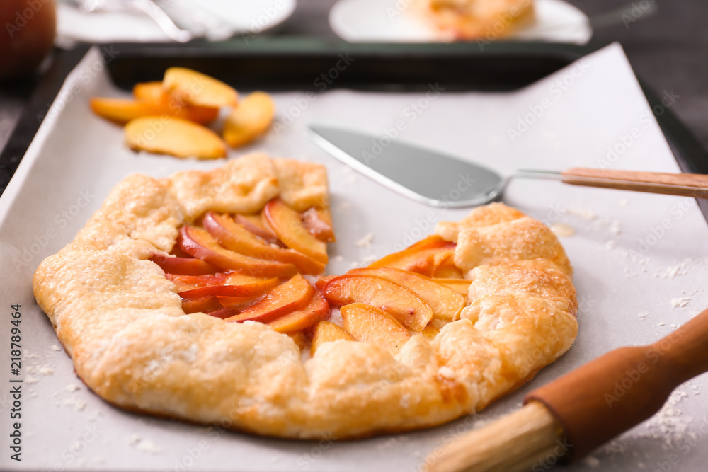 Parchment with delicious peach galette on baking tray Parchment with delicious peach galette on baking tray