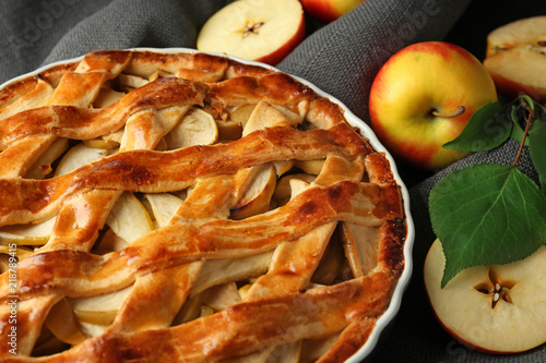 Dish with delicious apple pie on table